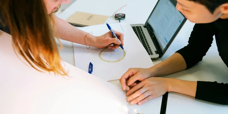 A CAD designer sketching a new model design with her coworker.