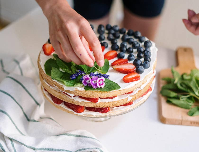 Cake Decorator decorating a cake with fruits and mint
