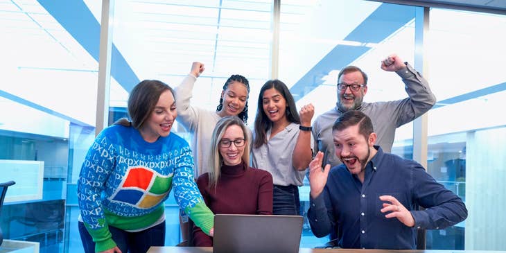 colleagues celebrating in the office after seeing the report on their manager's laptop