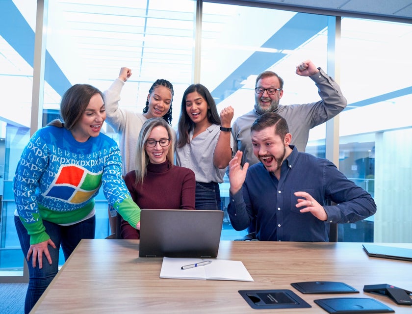 colleagues celebrating in the office after seeing the report on their manager's laptop