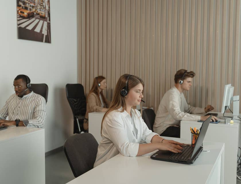 Call Center Representatives working on their designated workstations while wearing headsets and looking at their computers
