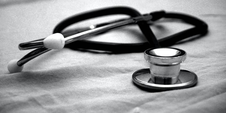 A cardiology technician's black and gray stethoscope on a white paper.