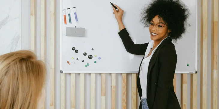 A woman pointing at a whiteboard.