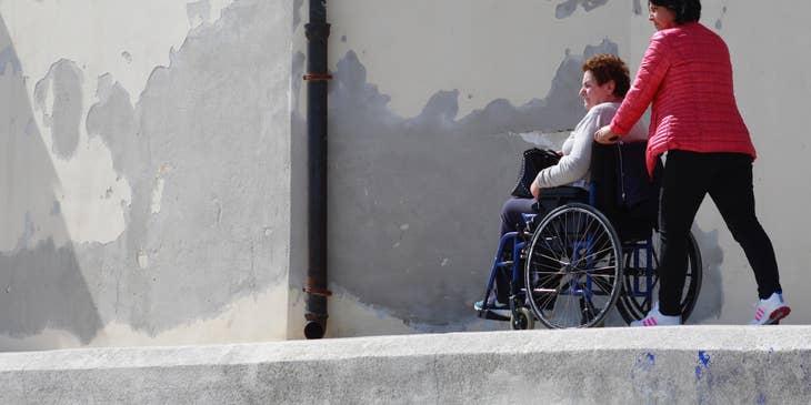 female Caregiver walking a patient on a wheelchair.