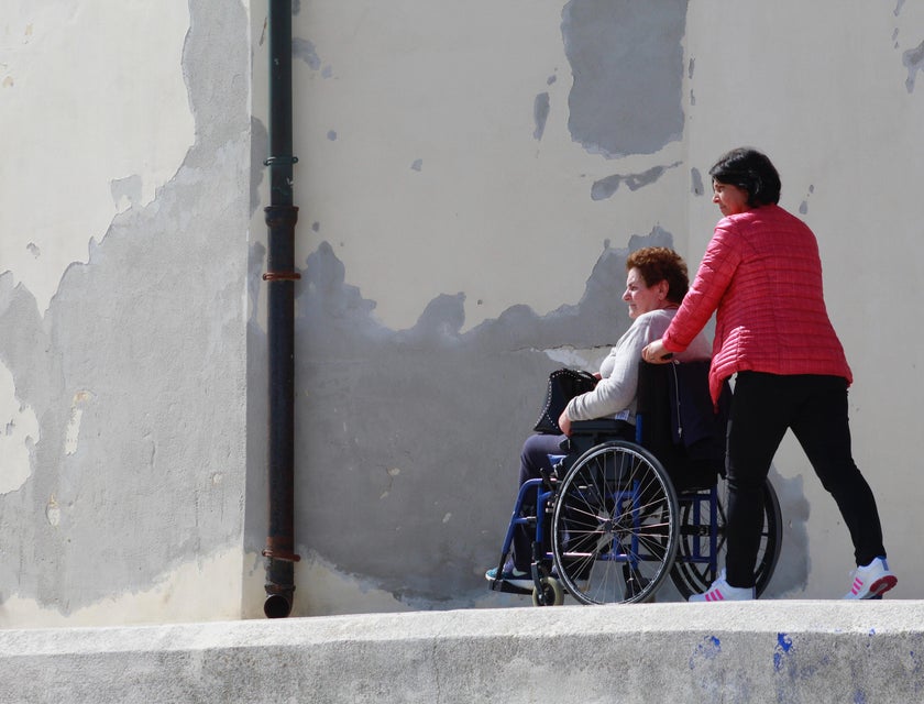 female Caregiver walking a patient on a wheelchair.