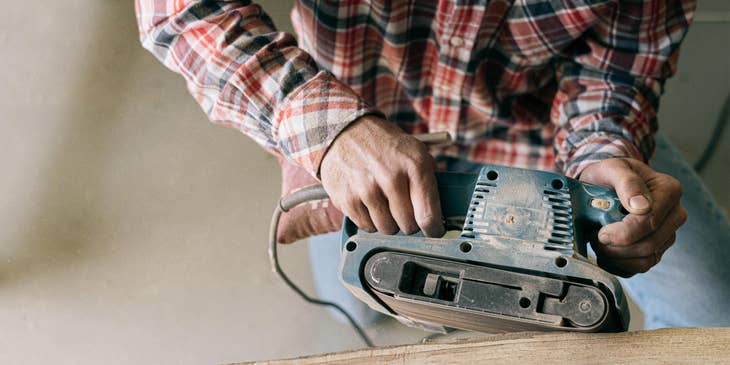 Carpenter sanding down a wooden board