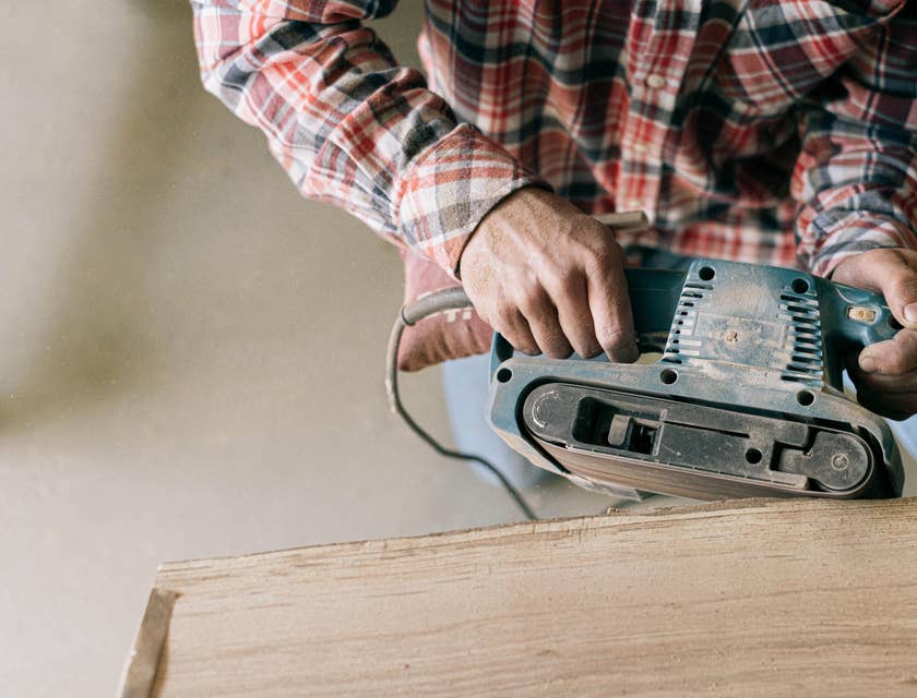 Carpenter sanding down a wooden board