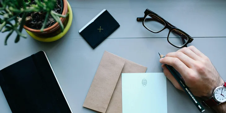 Un jefe escribiendo una carta de agradecimiento profesional para sus empleados más destacados.