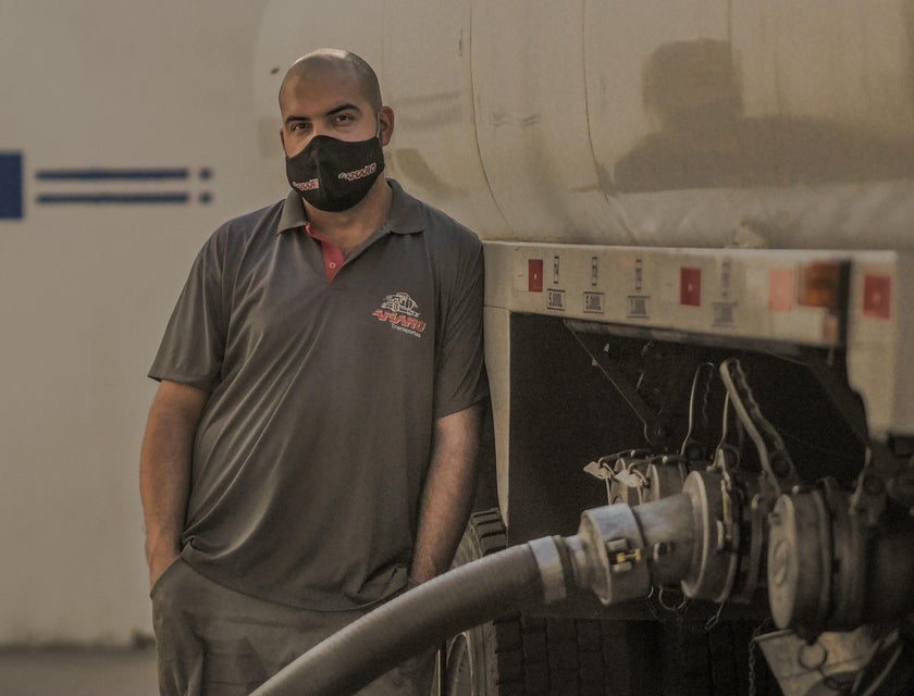 A CDL Driver loading and ensuring the truck is filled with oil before taking off for delivery.