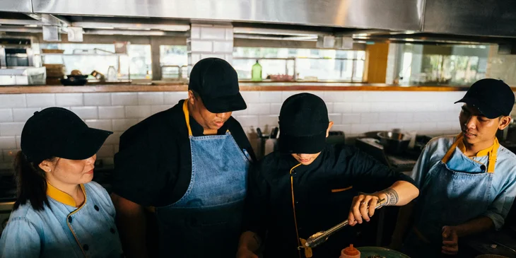 A chef de cuisine with his staff doing final touches before serving the food.