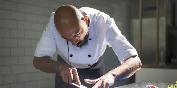 A chef de partie carefully slicing ingredients.