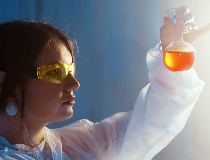 female Chemical Engineer looking at a glass vial containing an orange-colored liquid