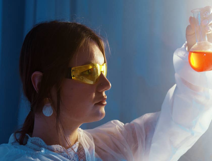 female Chemical Engineer looking at a glass vial containing an orange-colored liquid