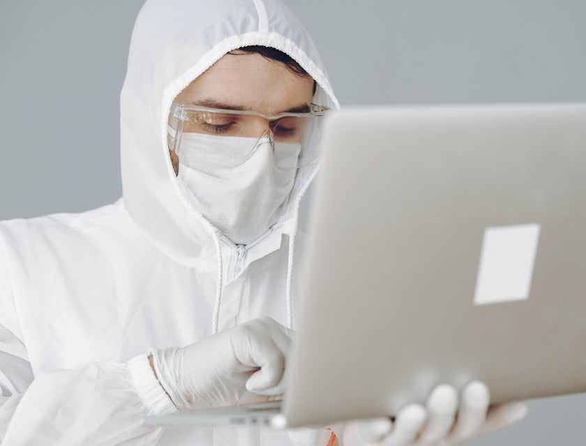 A Chemical Operator wearing a safety gear using his laptop and entering informations gathered on a database.