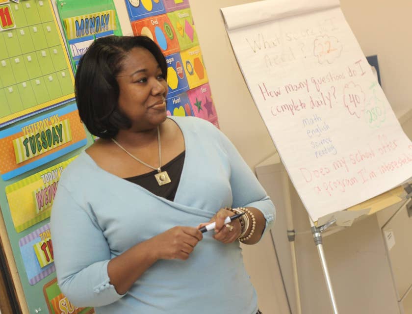 Childcare Assistant listens to students while teaching.