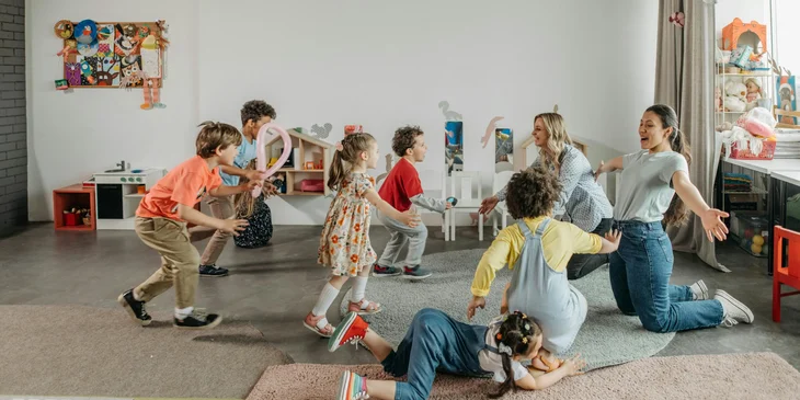 Two female childcare assistants playing with the kids.