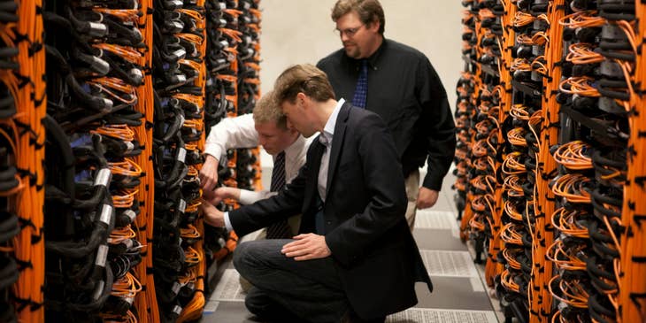 Cisco Network Engineers holding the wires and doing routine checks on the system