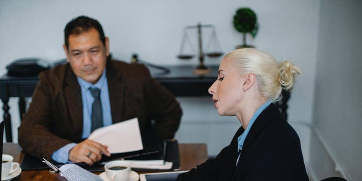 A Female Civil Rights Attorney showing a document to a client and providing legal advice.