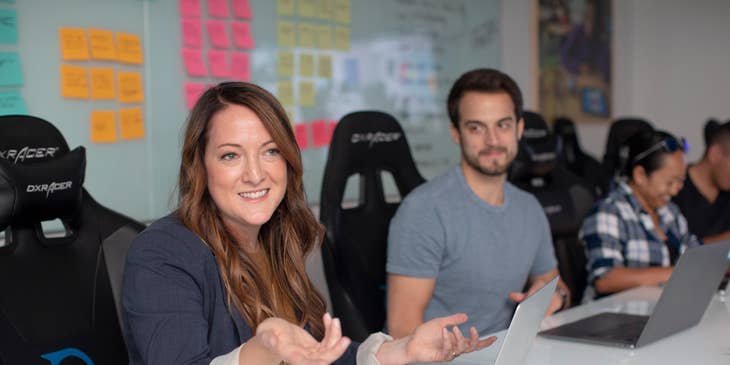 female Client Relationship Manager wearing black long-sleeved coat meeting with the client's team while sitting inside the office