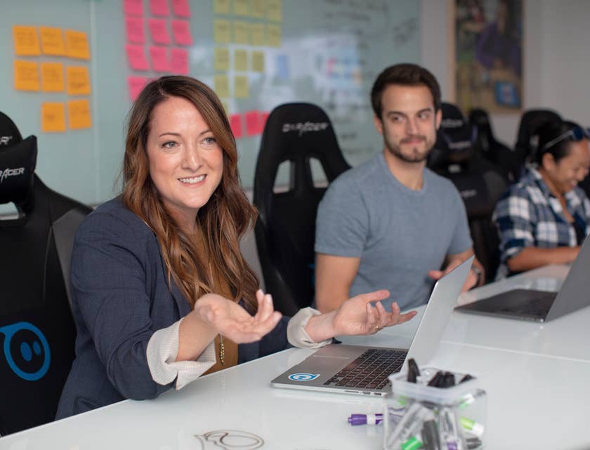 female Client Relationship Manager wearing black long-sleeved coat meeting with the client's team while sitting inside the office