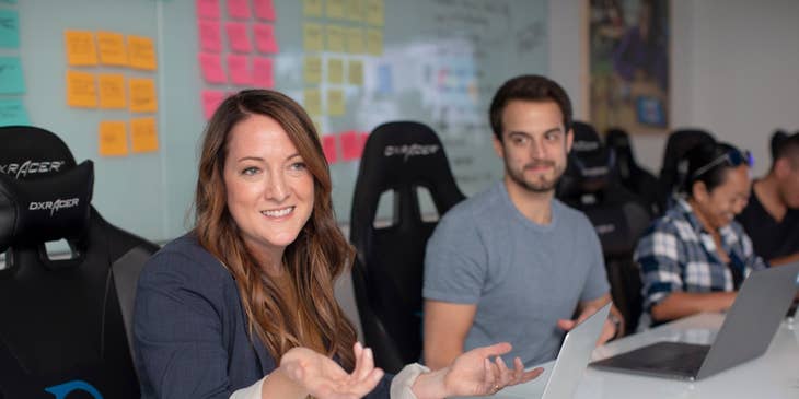 female Client Relationship Manager wearing black long-sleeved coat meeting with the client's team while sitting inside the office