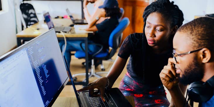 Client Services Manager sitting and pointing out something on the laptop while her male colleague looks on