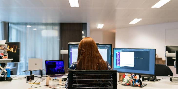 female Client Servicing Executive working at the office with her back on camera and sitting in front of her workstation