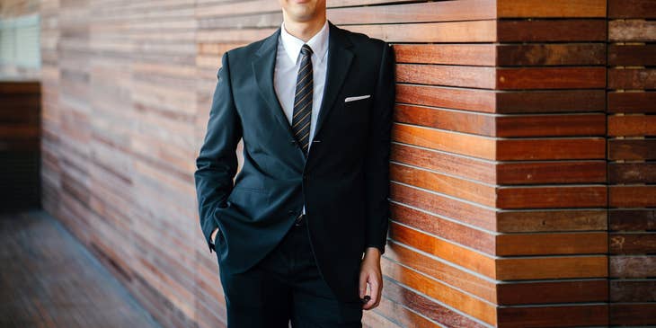 Collections Officer wearing a business suit while leaning on the office wall