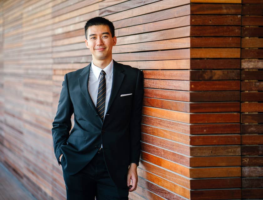 Collections Officer wearing a business suit while leaning on the office wall