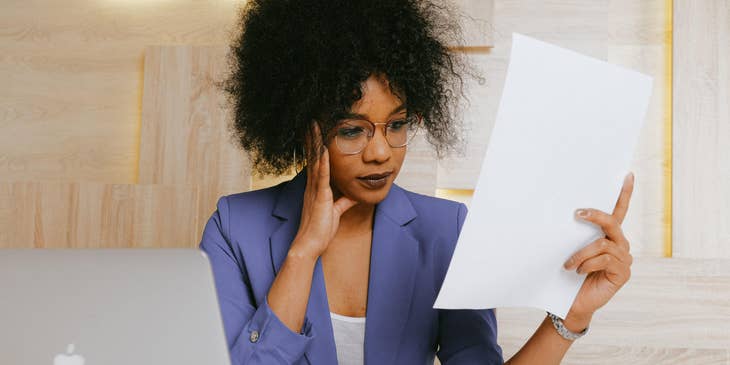 A commodity manager working in front of her laptop looking at a piece of paper.