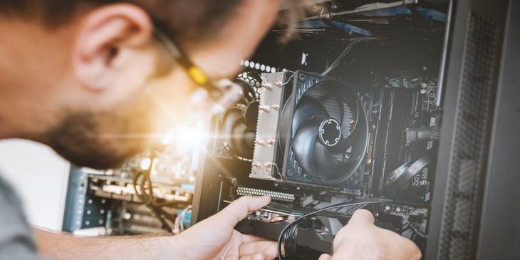 Computer Hardware Engineer fitting a graphics card to the slot for testing purposes