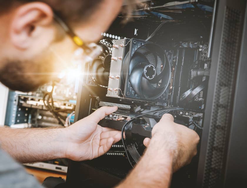 Computer Hardware Engineer fitting a graphics card to the slot for testing purposes