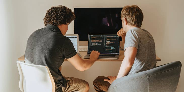 Computer Systems Analysts sitting in front of an open laptop and discussing the running program