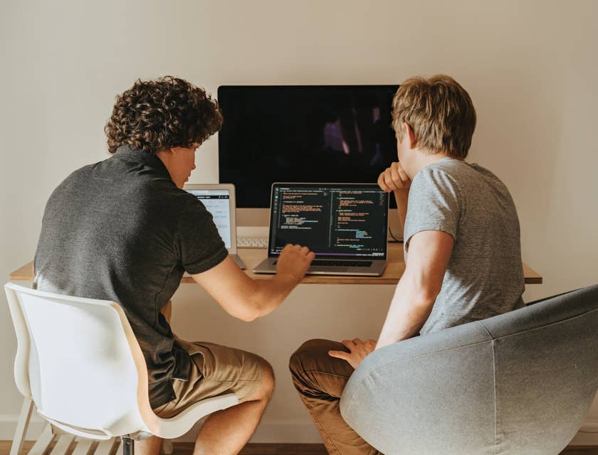 Computer Systems Analysts sitting in front of an open laptop and discussing the running program