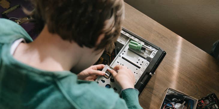 A computer technician looking down and holding a motherboard component to set up the processing unit.