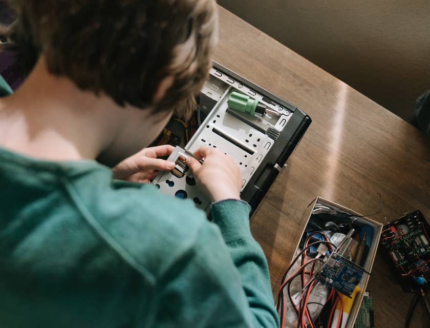 A computer technician looking down and holding a motherboard component to set up the processing unit.