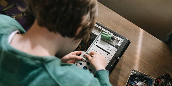 A computer technician looking down and holding a motherboard component to set up the processing unit.
