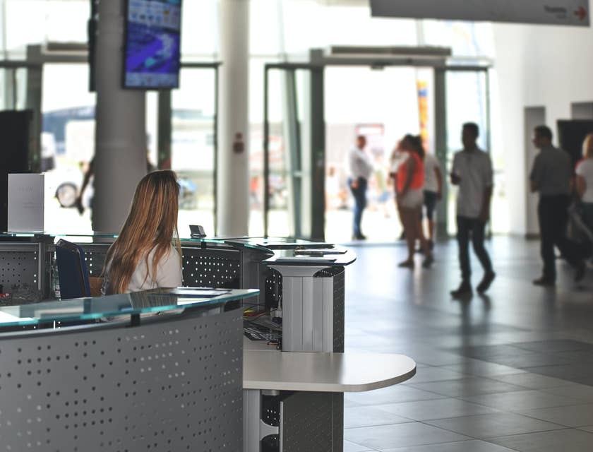 female Concierge sitting at the reception desk and looking over at the building's entrance