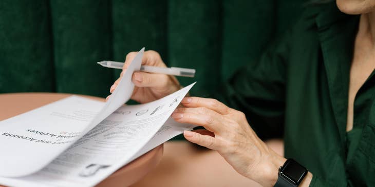 A Female Contract Analyst reviewing some contracts to ensure adherence to legal requirements by law.