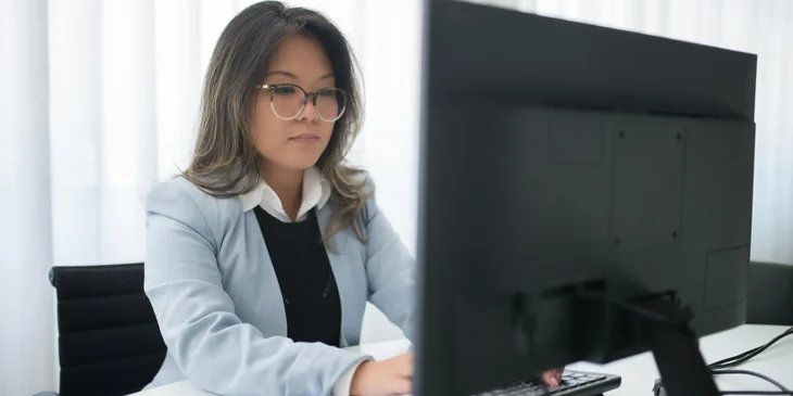 A female contract specialist drafting contracts for clients on her computer.