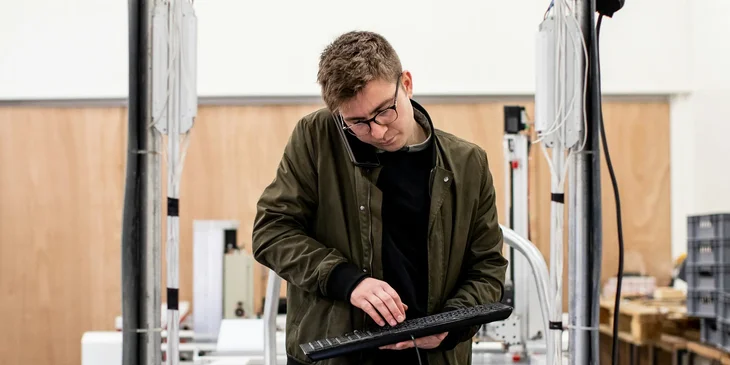 A controls engineer working holding a keyboard troubleshooting issues with hardware.
