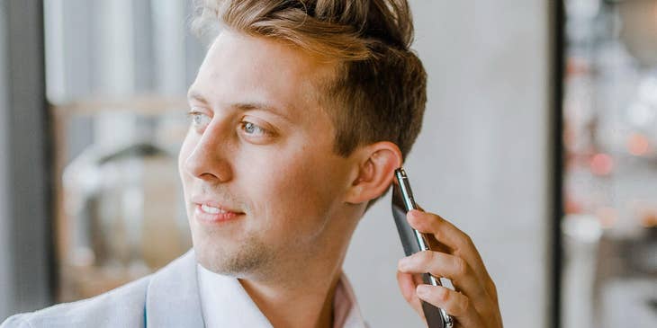 A corporate travel manager in a blue suit talking on his smartphone.