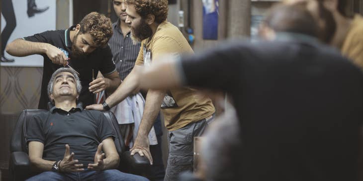 Cosmetology Instructor show student how to properly trim men's hair in a barbershop