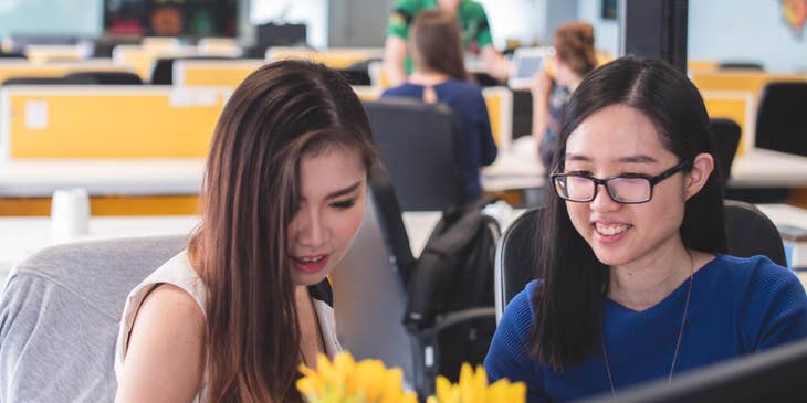 Creative Technologists sitting together on a desk and discussing a detail on the project they are both working on