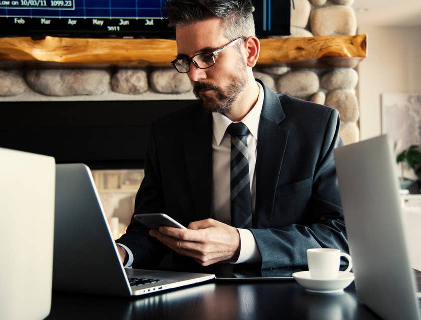 Credit Specialist wearing a business suit and holding his phone while looking at his laptop