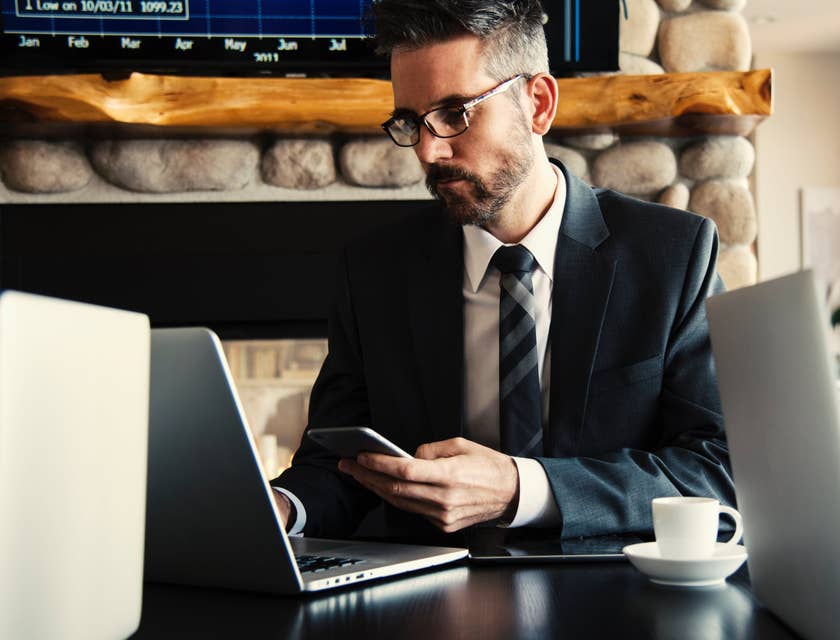 Credit Specialist wearing a business suit and holding his phone while looking at his laptop