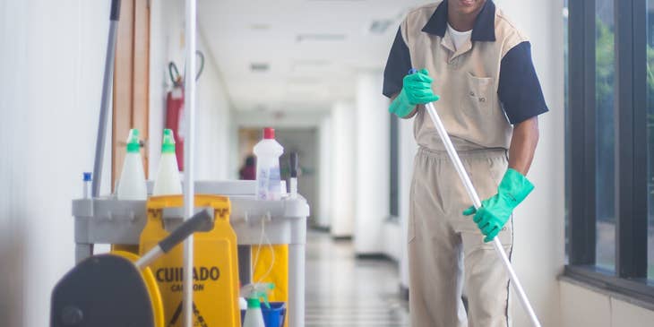 Custodian cleaning a hallway in a building