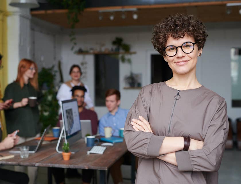 female Customer Service Manager smiling while her team on the background is on break