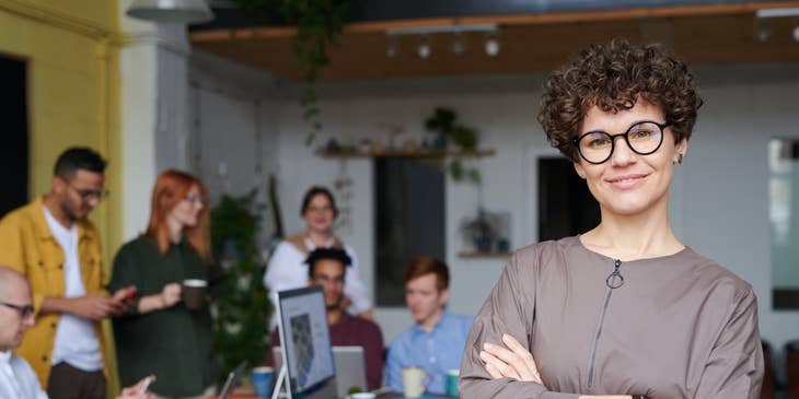 female Customer Service Manager smiling while her team on the background is on break