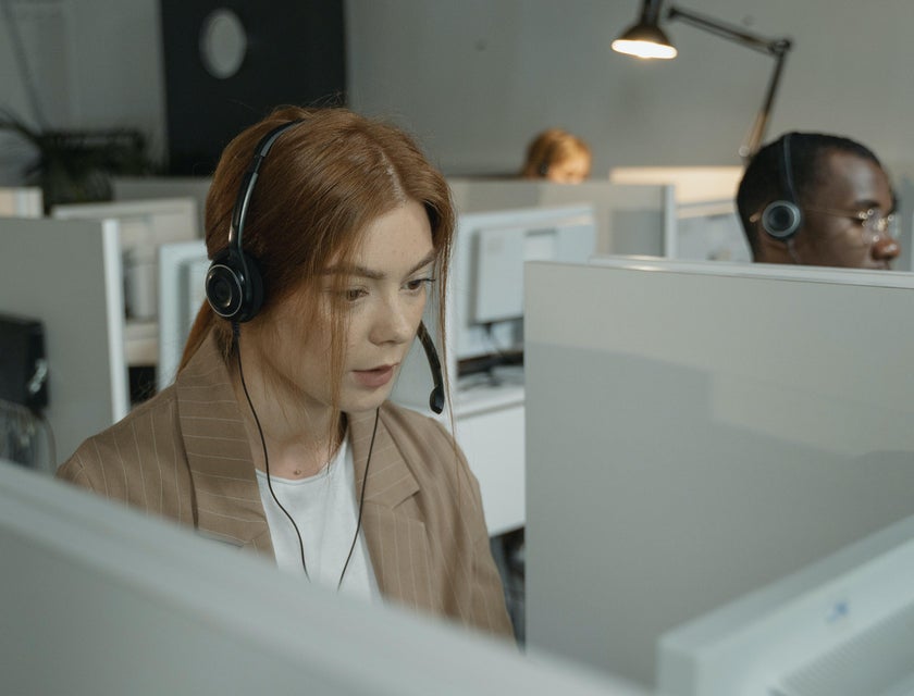 female Customer Support Representative wearing her headset while looking at the computer on her workstation